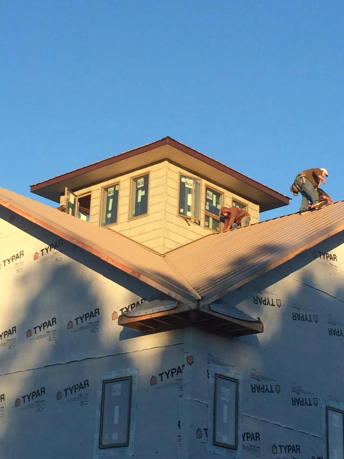 Roofers working around a rooftop cupola on a new metal roof at sunset — Roof Waterproofing in Yorktown by Roofing Brothers